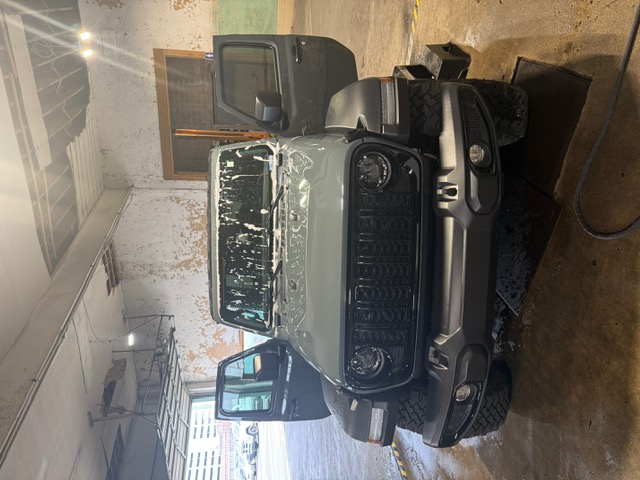Green Jeep Wrangler getting windshield cleaned at Capitol Glass