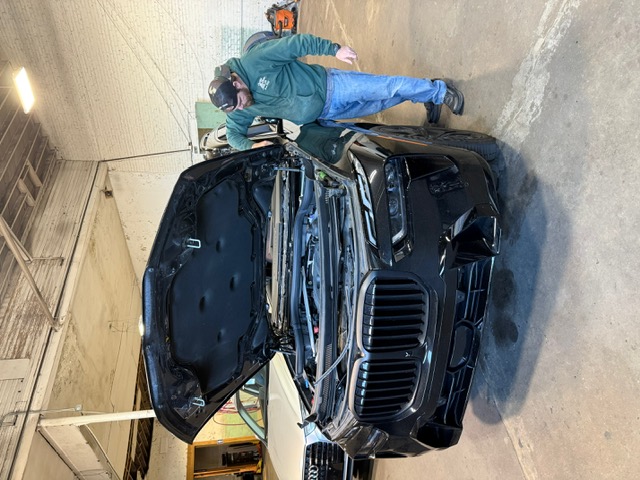 Technician servicing black BMW X7 with hood open at Capitol Glass