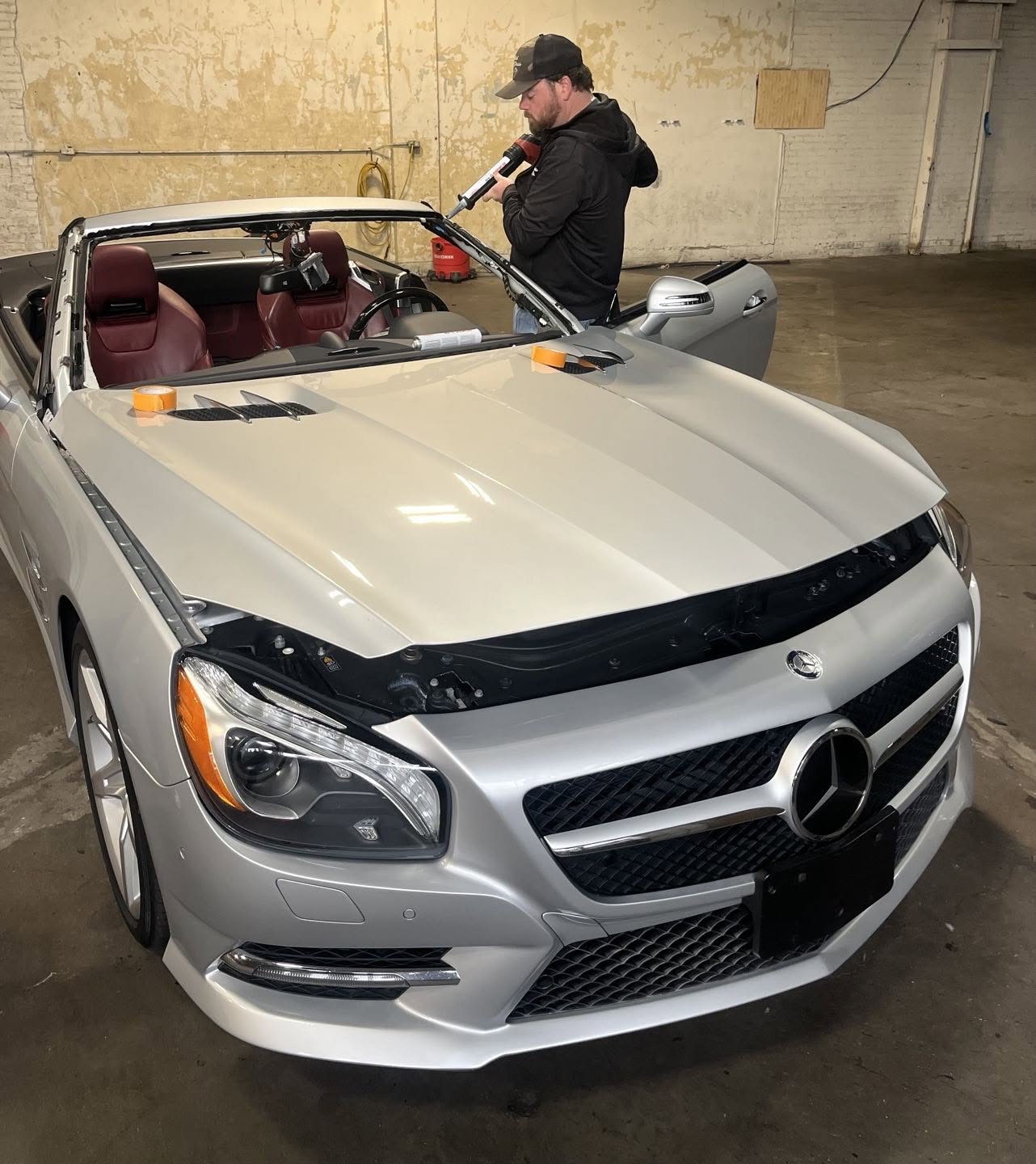 Capitol Glass technician repairing the windshield of a silver Mercedes-Benz convertible in the Little Rock shop