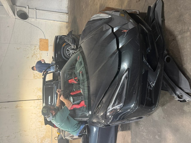 Technician installing windshield on black C8 Corvette convertible