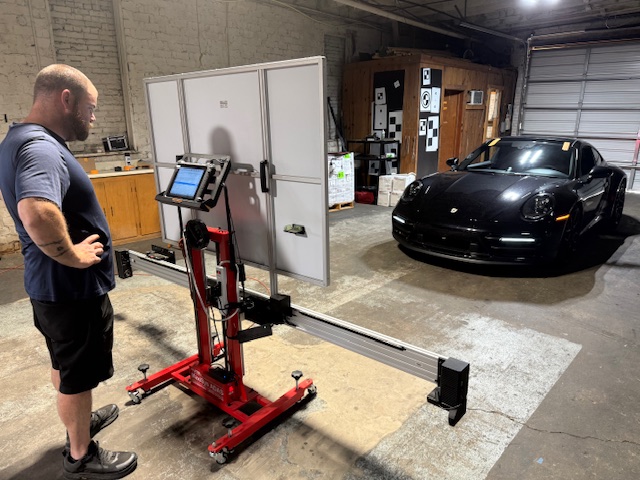 Technician performing ADAS recalibration on a black Porsche 911 at Capitol Glass