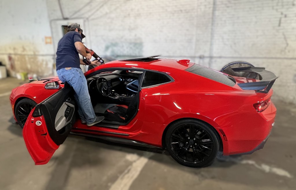 Technician installing glass on a red Chevrolet Camaro sport coupe