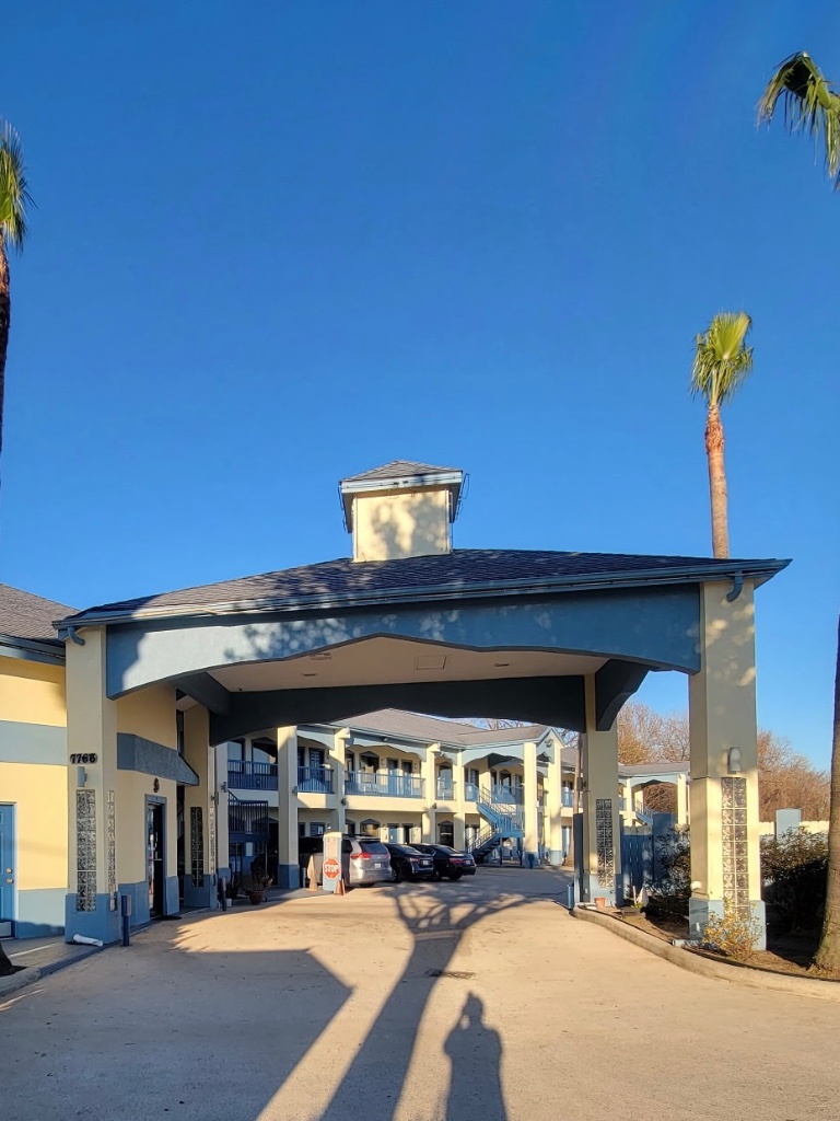 A two-story building with a covered driveway and palm trees
