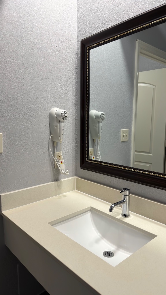 A bathroom sink with a mirror and hair dryer