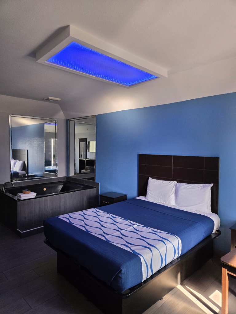A hotel room with a bed, bathtub, and mirror