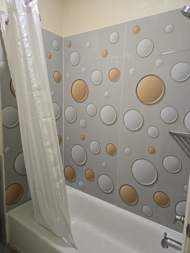 A bathroom with a shower curtain and a tub with decorative tile.