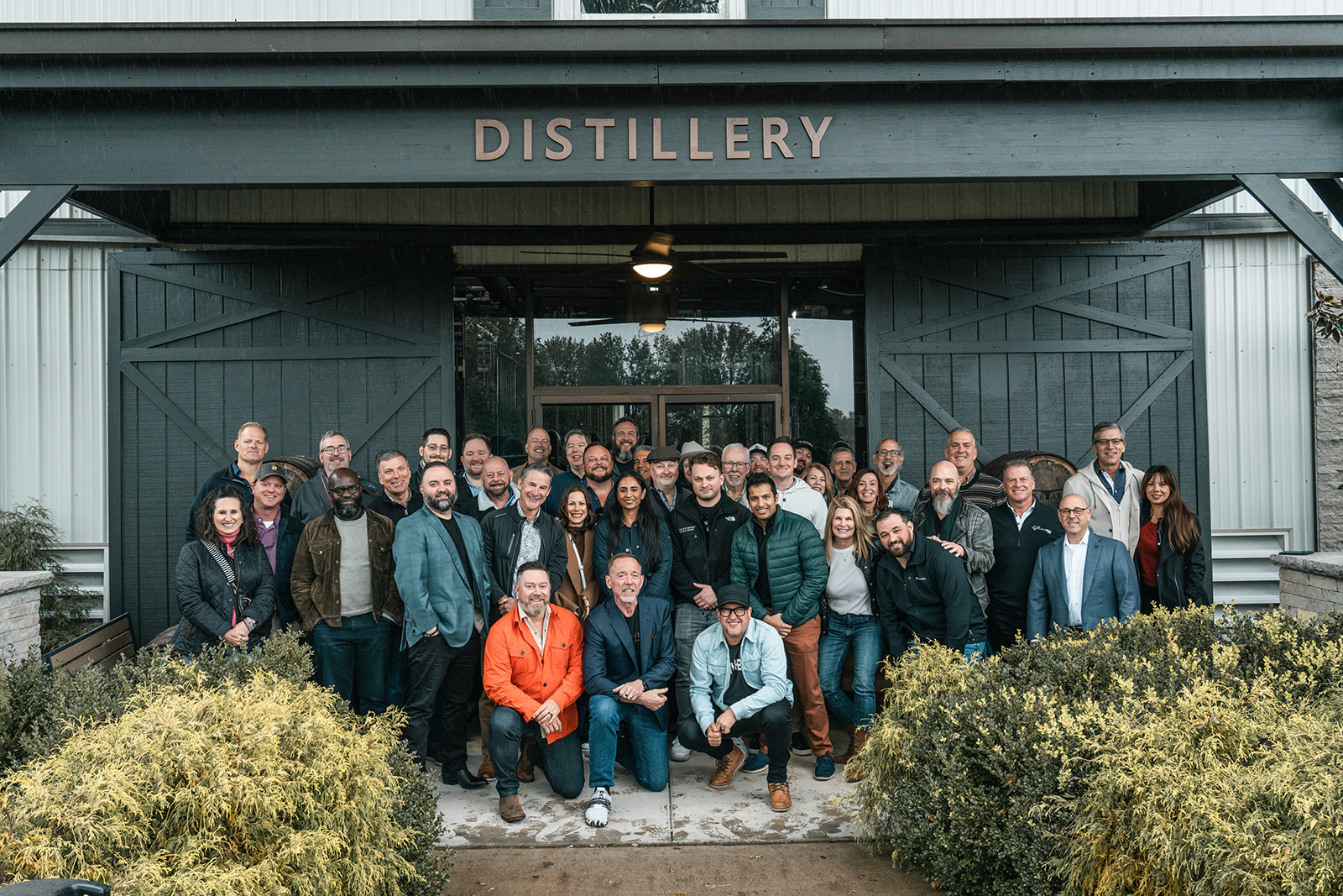 The full room of members gathered outside the distillery doors at a Social.