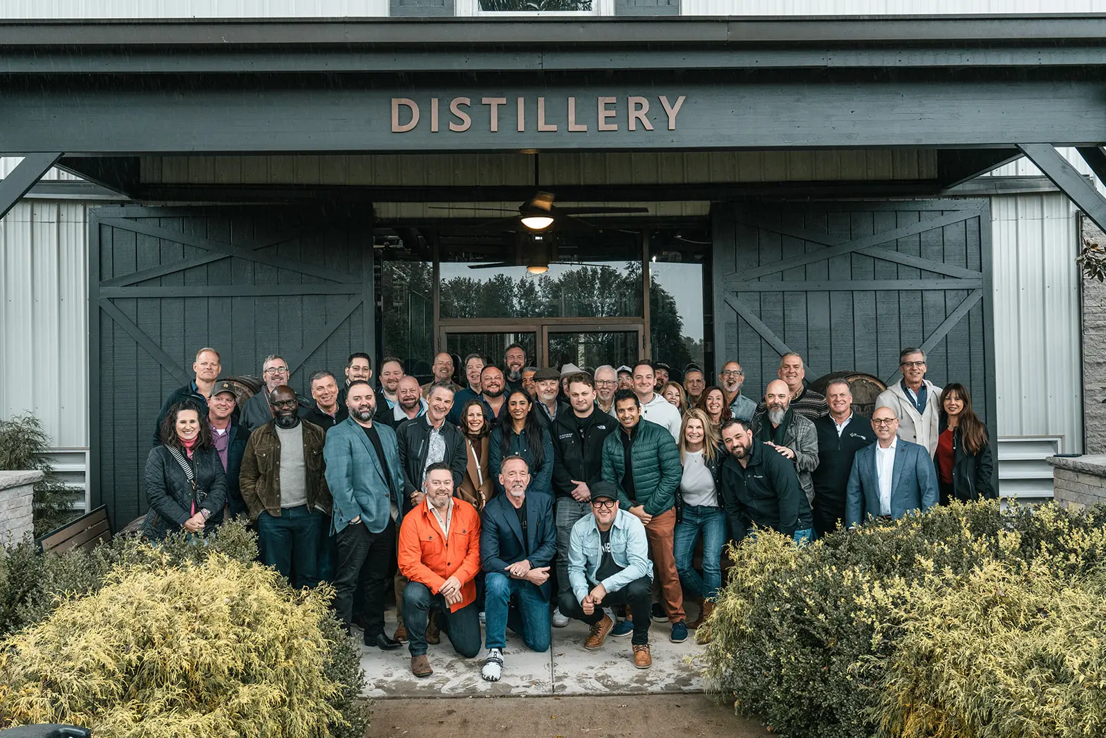 The full room of members gathered outside the distillery doors at a Social.