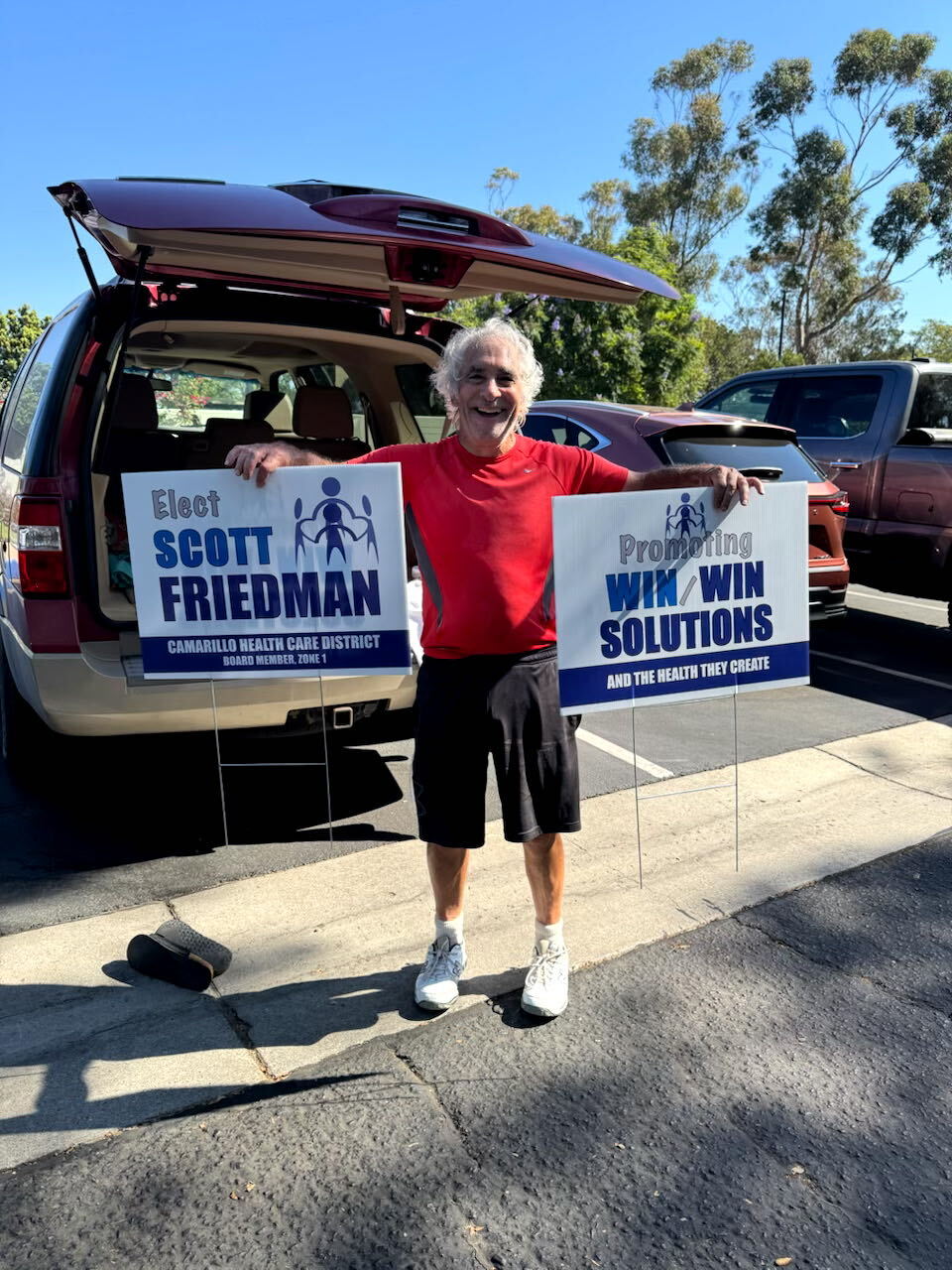 Scott Friedman holding campaign signs for Camarillo Health Care District Board Member, Zone 1 — promoting win/win solutions