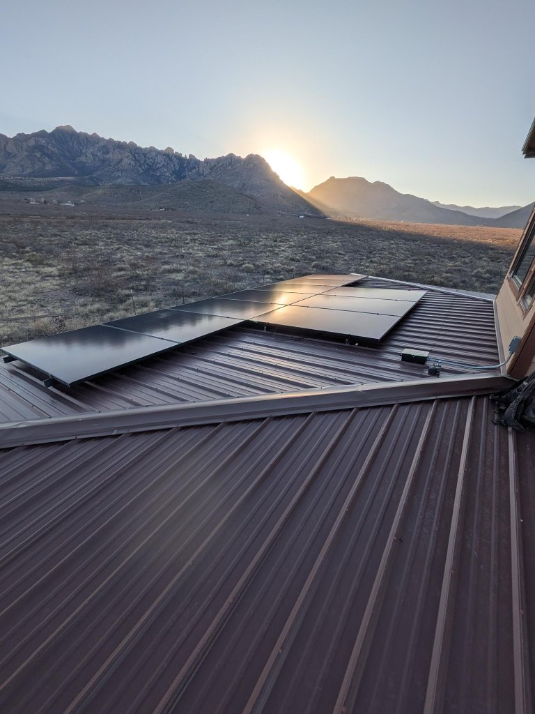 Solar panels on a metal roof with mountain sunrise