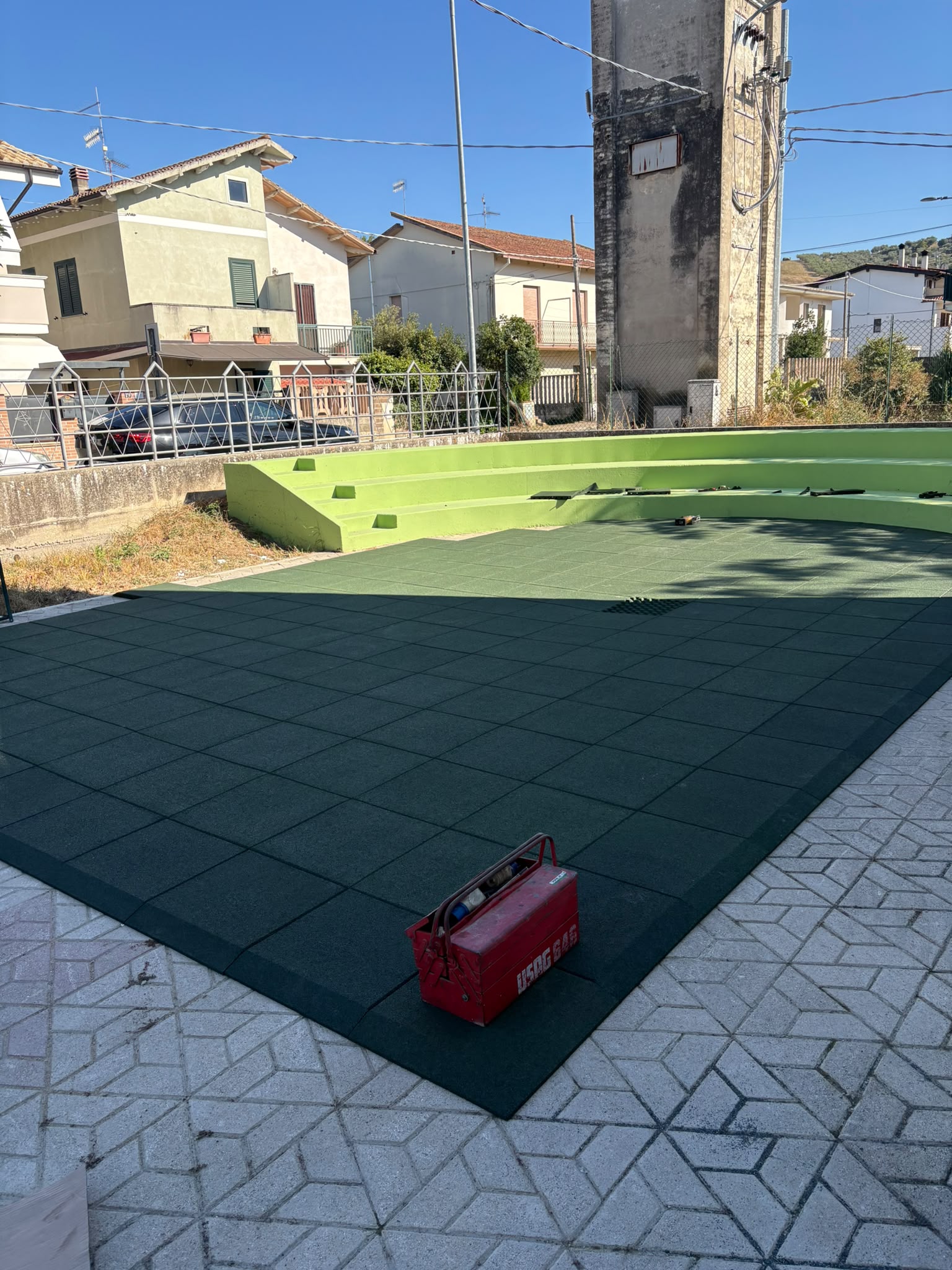 Area gioco esterna del nuovo asilo nido di Moscufo con pavimentazione antitrauma verde, giochi in legno e gradonata verde lime