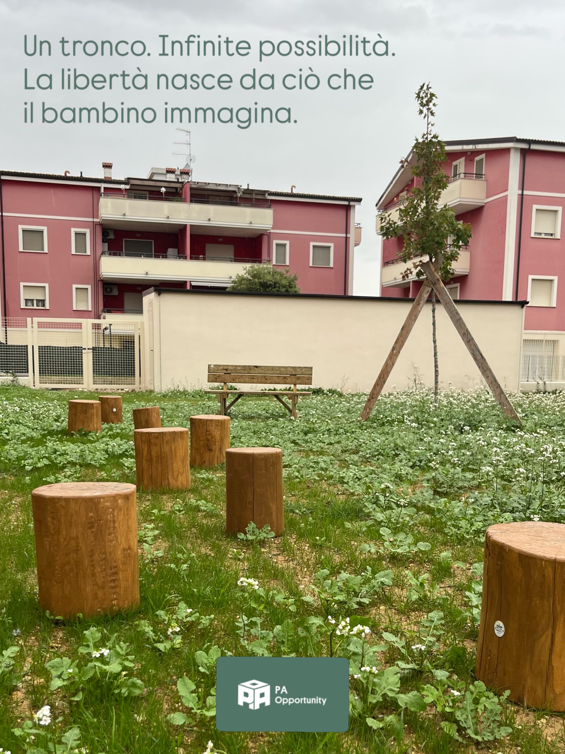 Giardino esterno di un nuovo asilo nido a Montesilvano (PE) arredato con sedute in legno, tronchi, cavalletti e spazi verdi per attività educative all'aperto, con edificio scolastico sullo sfondo.