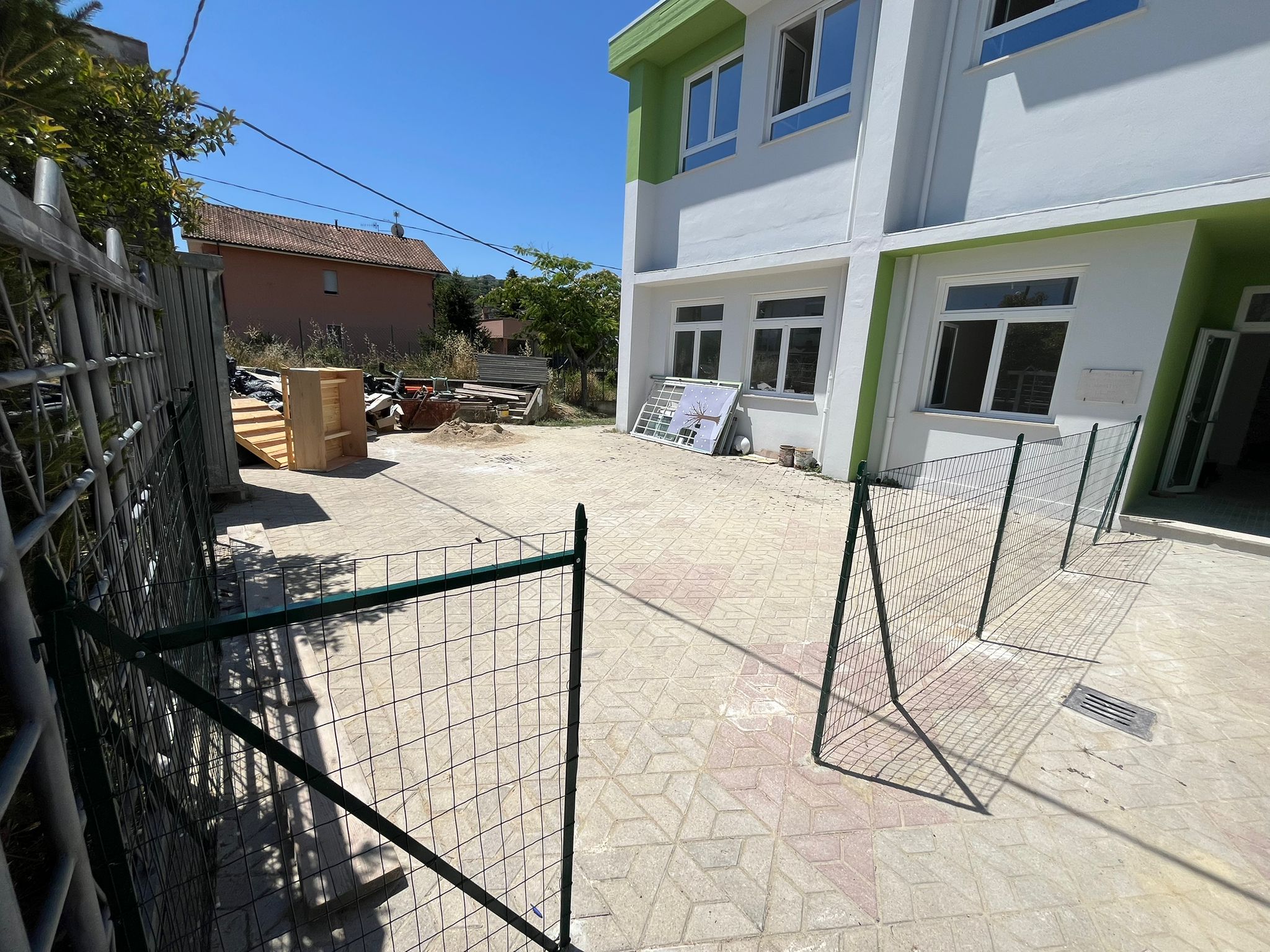 Area gioco esterna del nuovo asilo nido di Moscufo con pavimentazione antitrauma verde, giochi in legno e gradonata verde lime