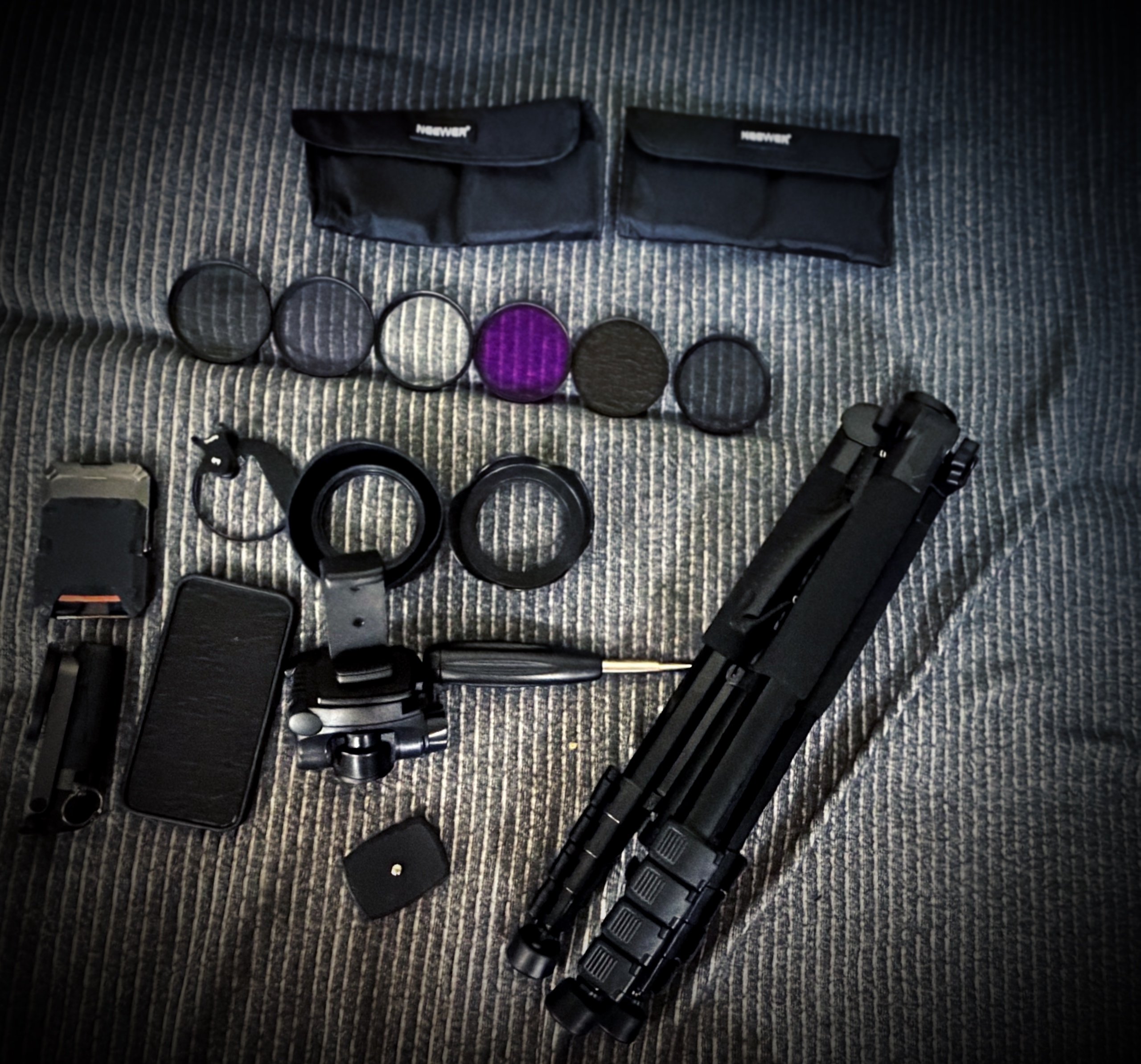 Mobile photography gear flat lay — lens filter set, phone clamp, tripod and carrying pouches