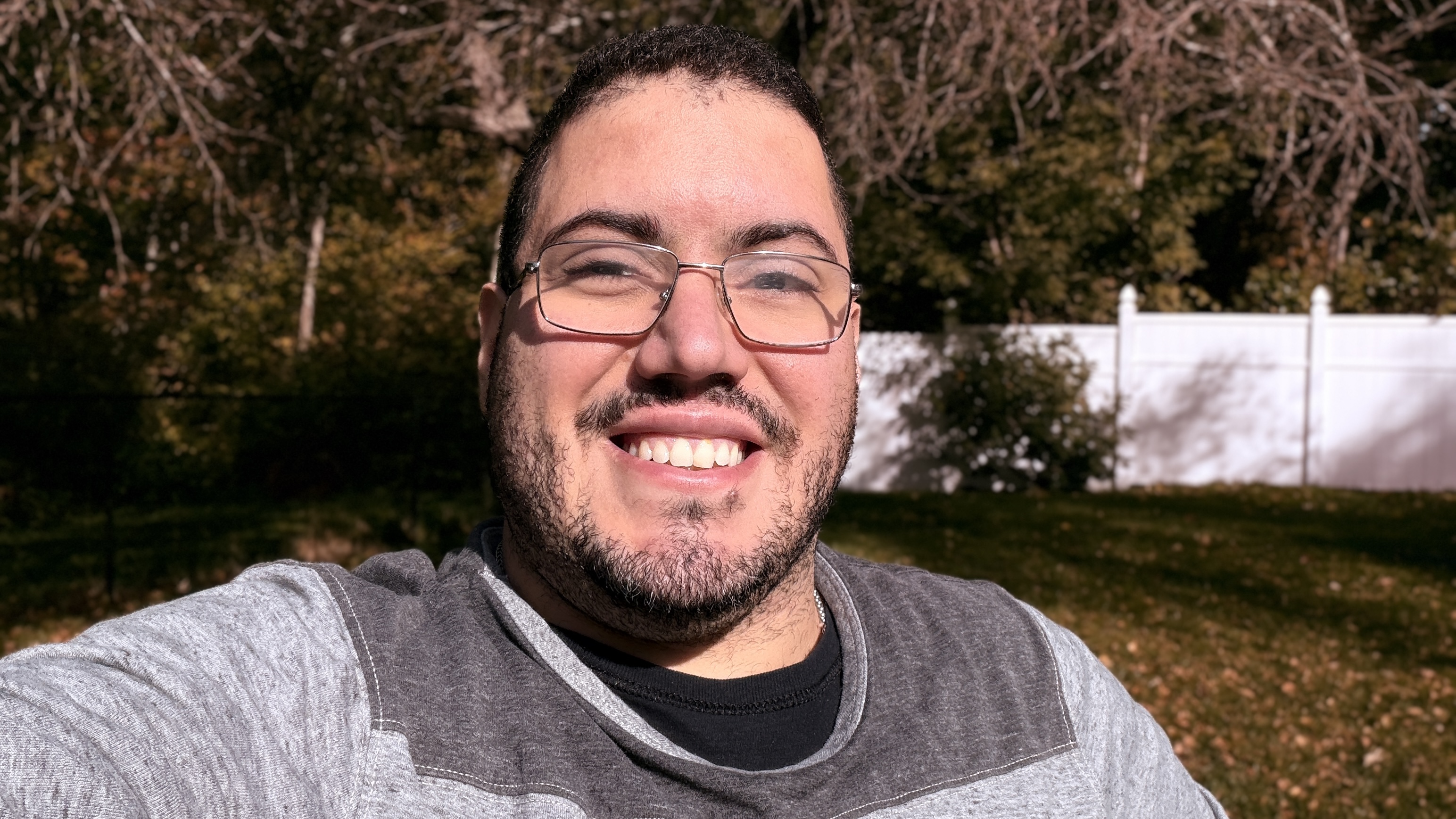 Self-portrait in warm evening light with an autumn backyard behind