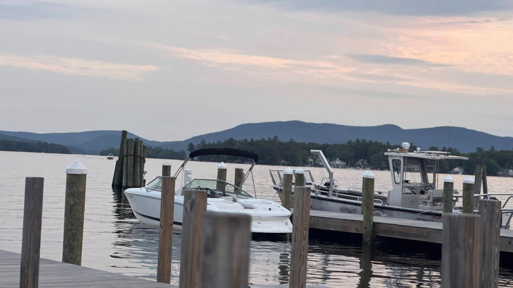 Boats moored at dock with mountain backdrop