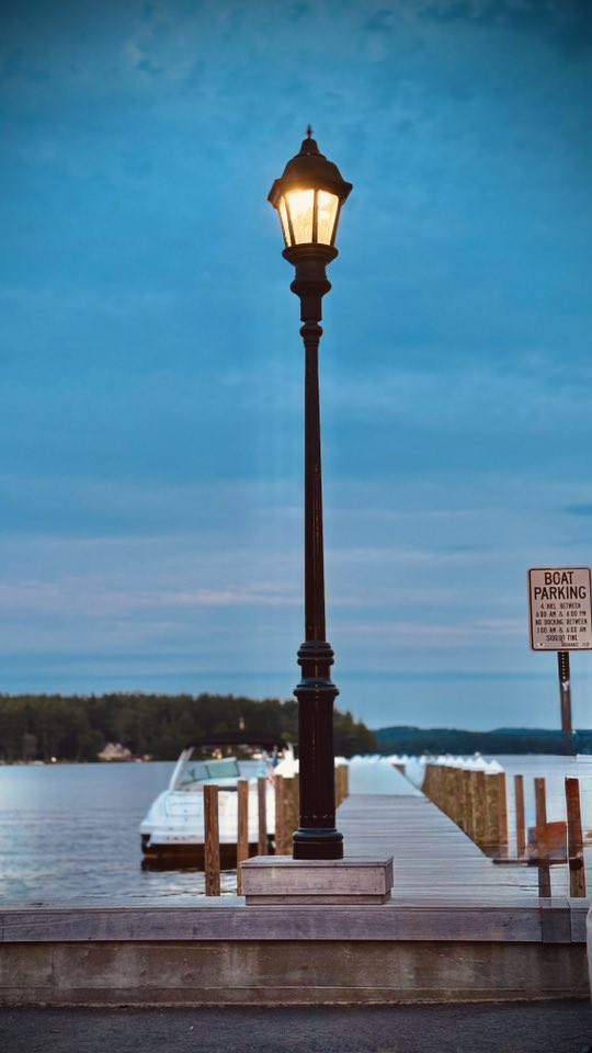 Glowing street lamp on marina dock at dusk