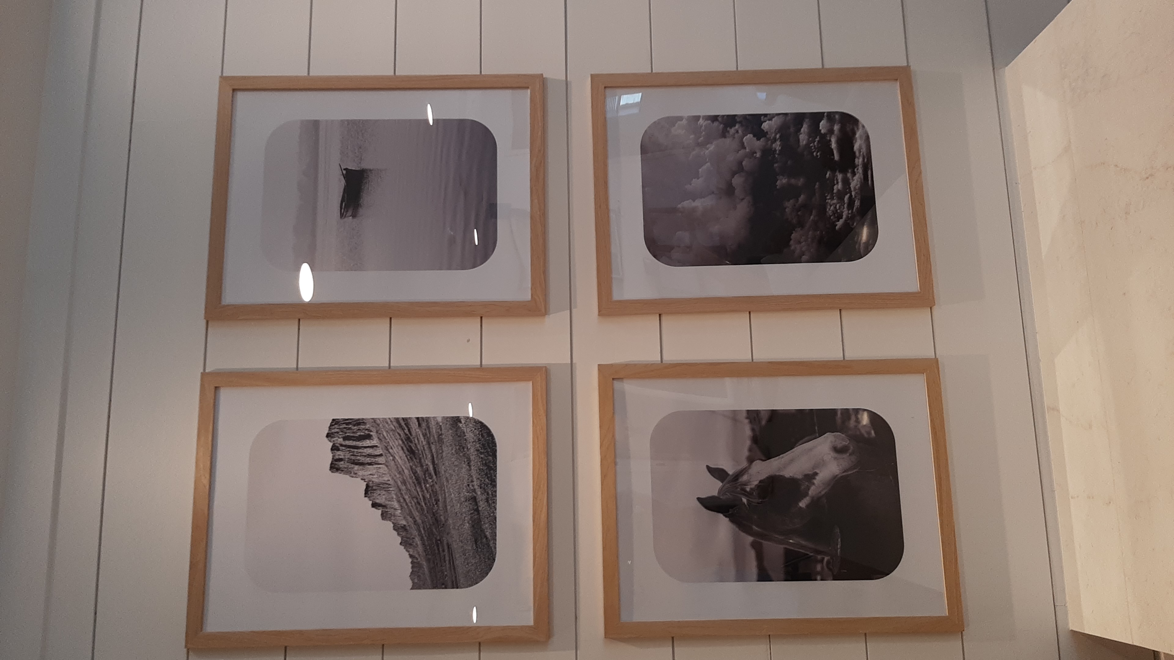 Four-Piece Framed Photo Grid in Edmond, OK | Redhawk Handyman Four black-and-white framed photographs installed in a two-by-two grid on a shiplap wall above a reception counter in a new Edmond, OK apartment community