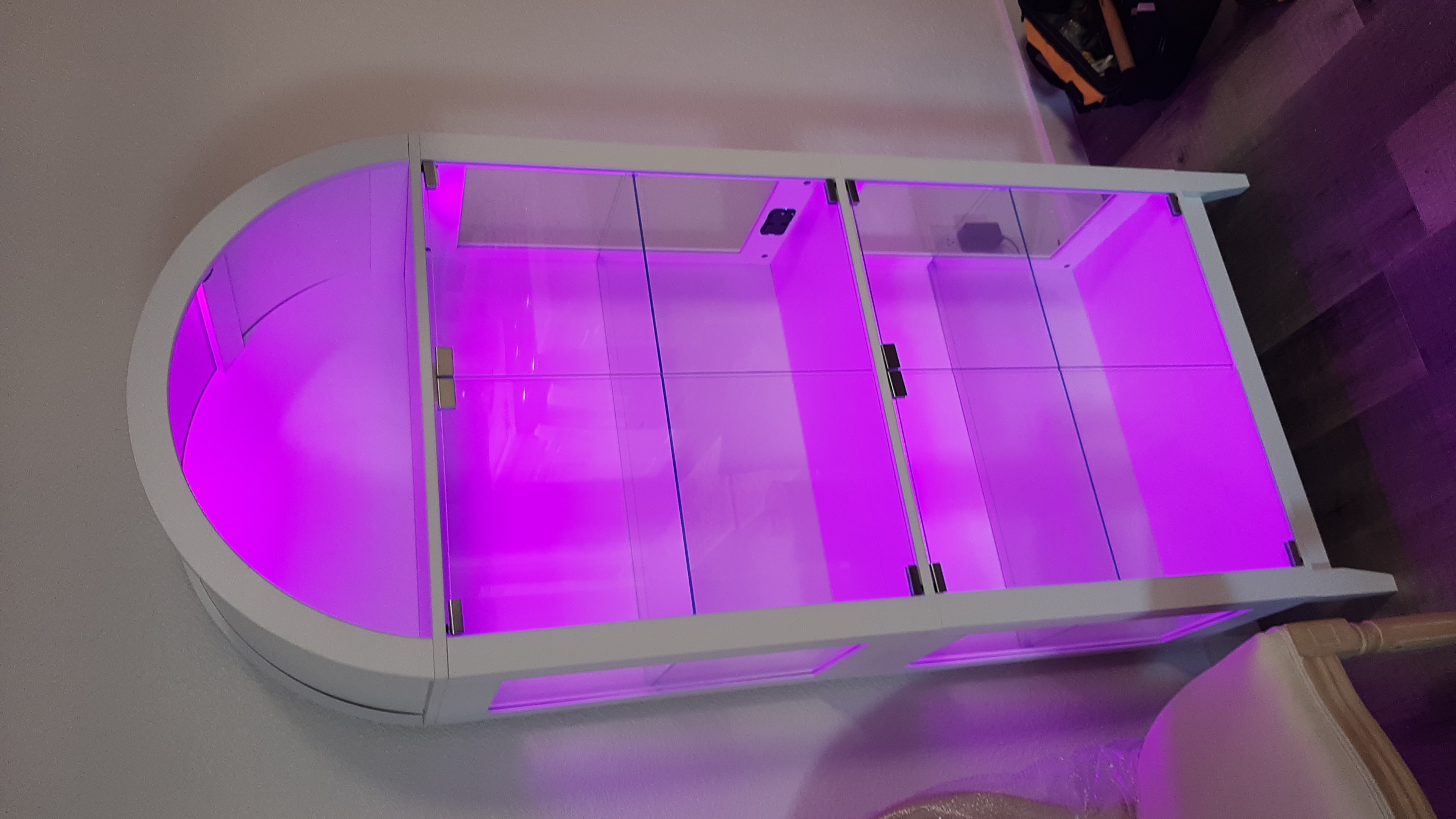 White lighted glass display cabinet with magenta LED interior lighting, freshly assembled in a Norman, OK home