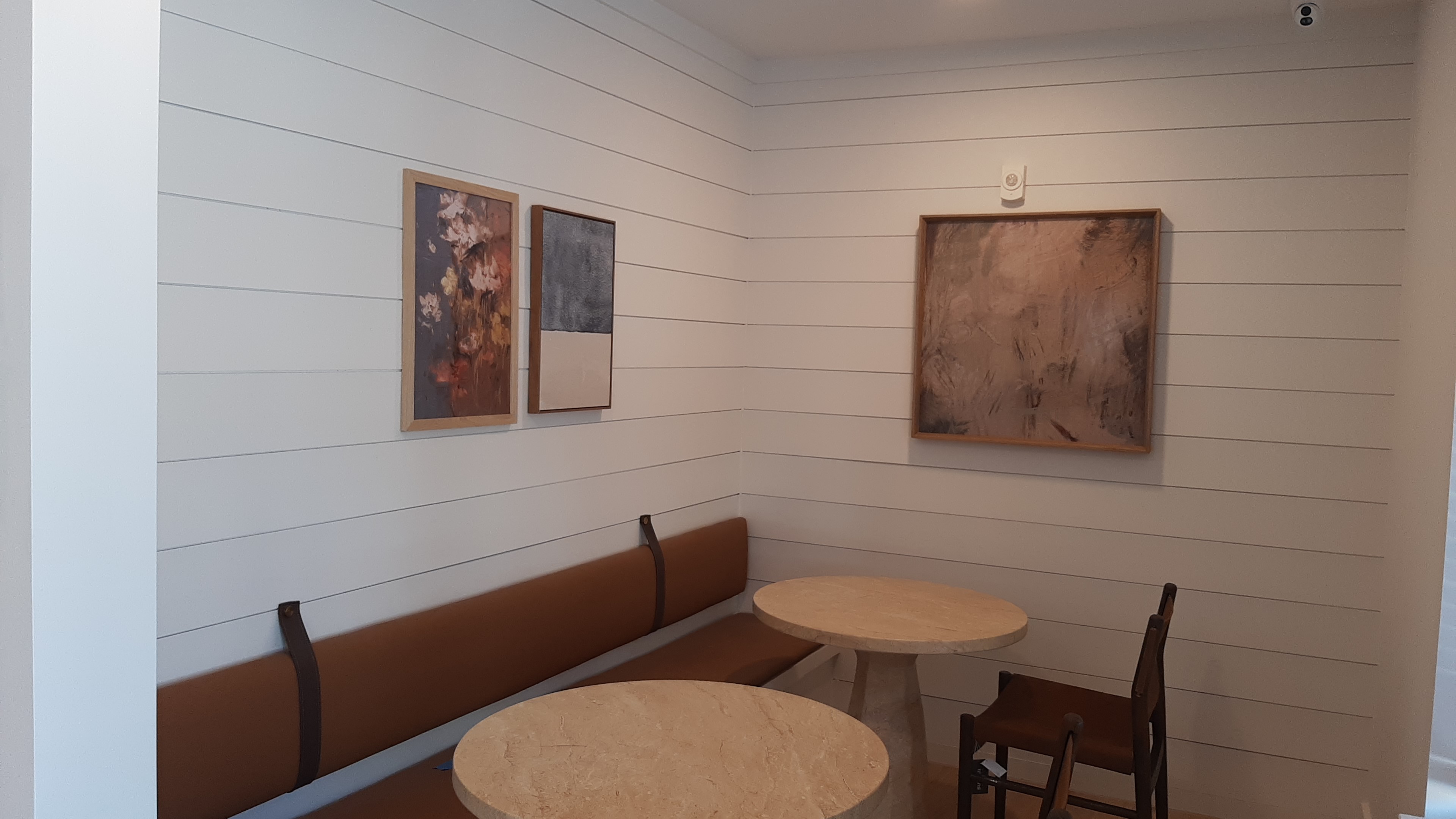 Three framed art pieces installed above a banquette in the coffee nook of a new Edmond, OK apartment community