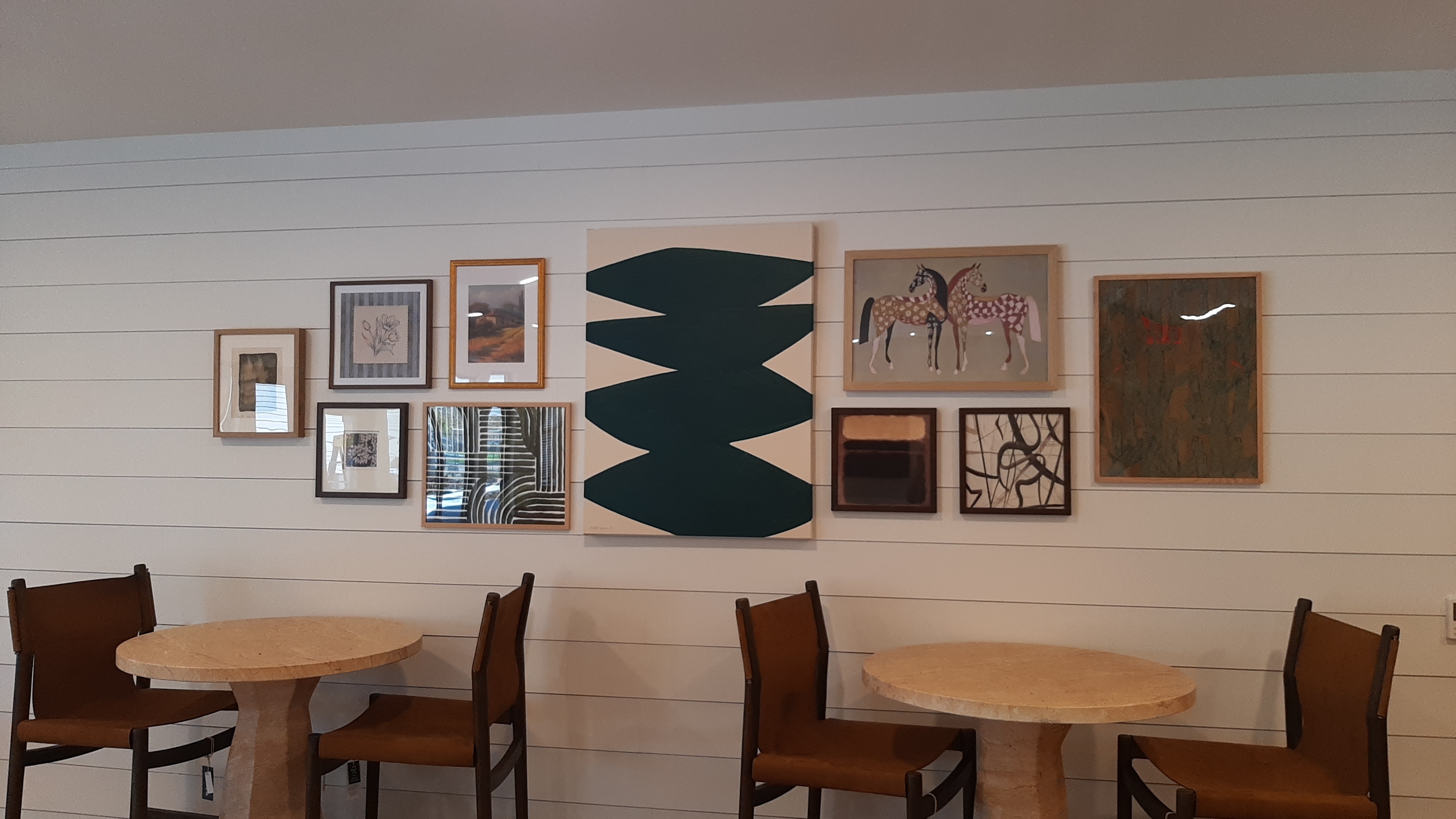 Salon-style gallery wall of framed art installed above a resident coffee bar in a new Edmond, OK apartment leasing lounge
