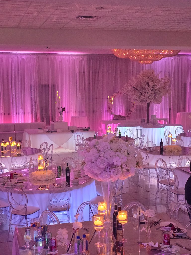 Wedding reception with white floral centerpieces and pink lighting