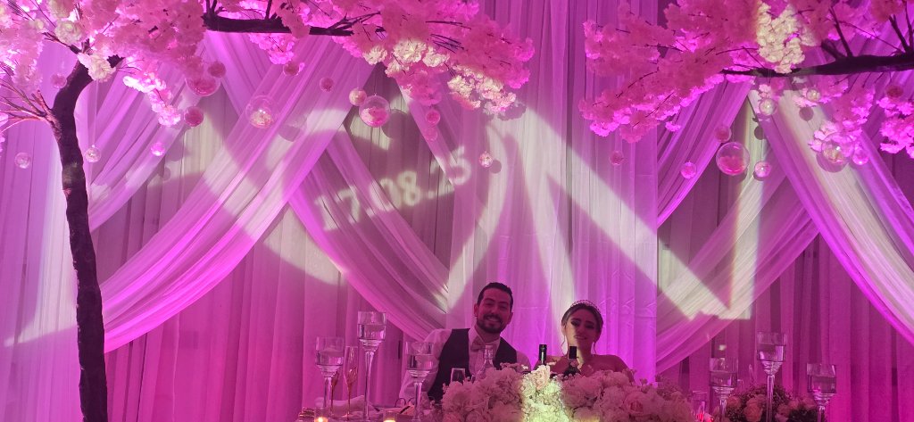 Wedding head table with cherry blossom trees and pink lighting
