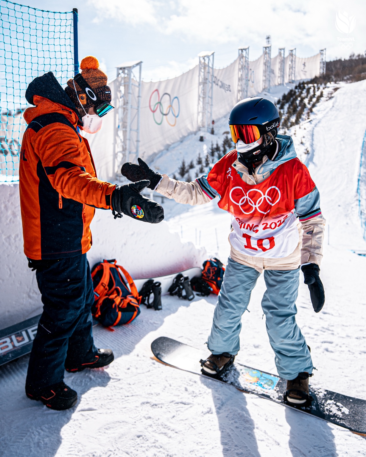 Fistbump tussen begeleider en snowboarder aan de rand van het Olympische parcours