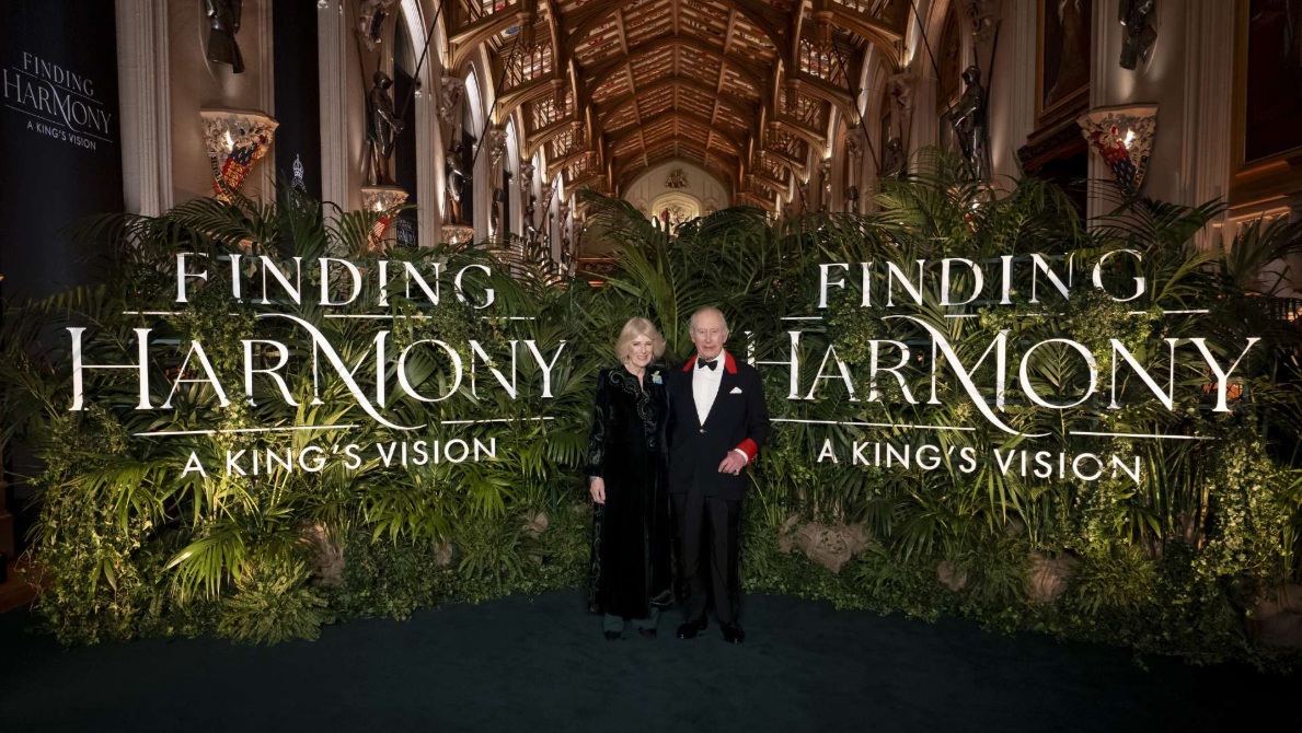 The King and Queen at the premiere of Finding Harmony: A King’s Vision, stood before a foliage wall bearing the film’s title.