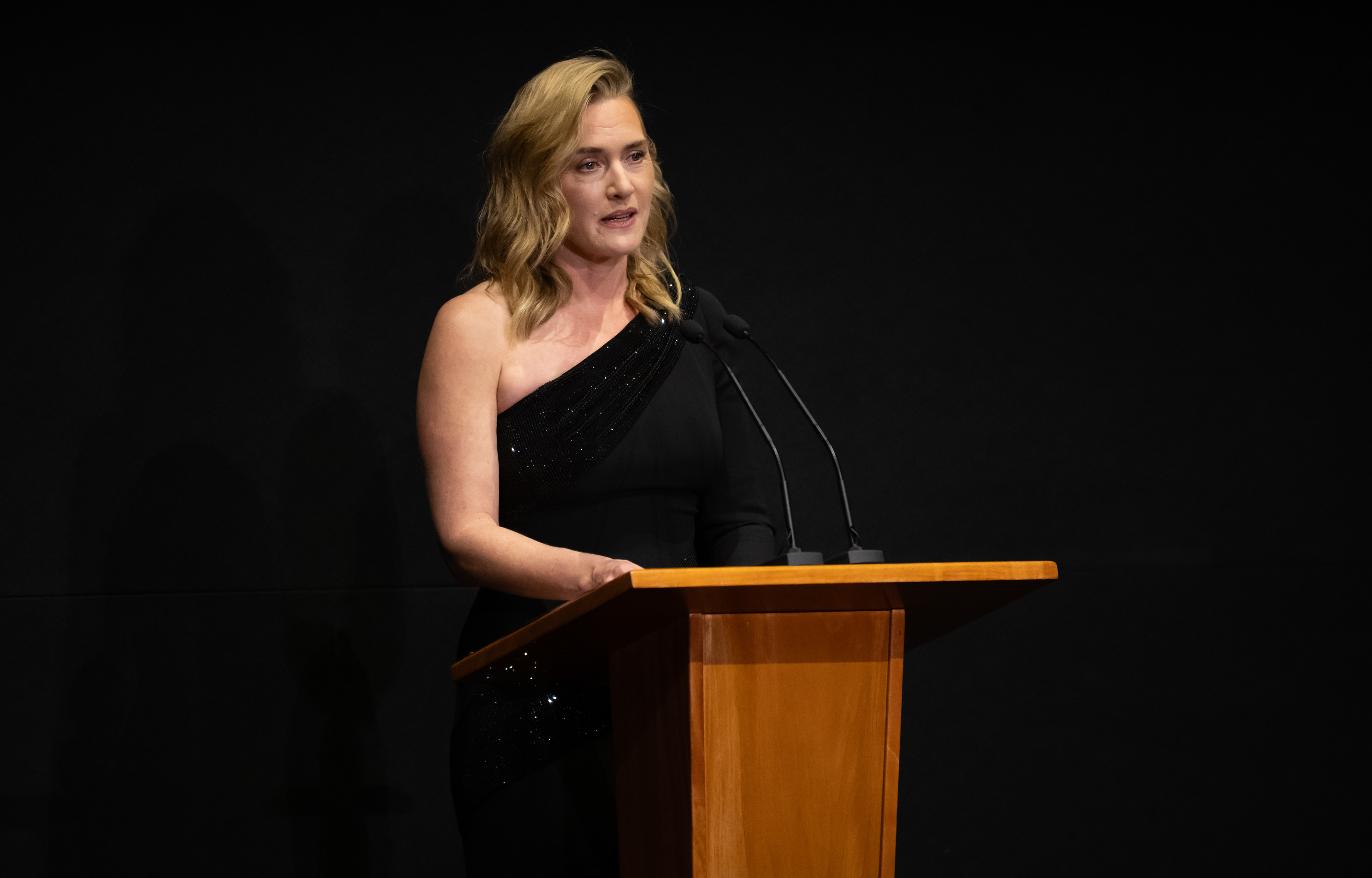 Kate Winslet speaking at a wooden lectern while introducing the documentary at the premiere.