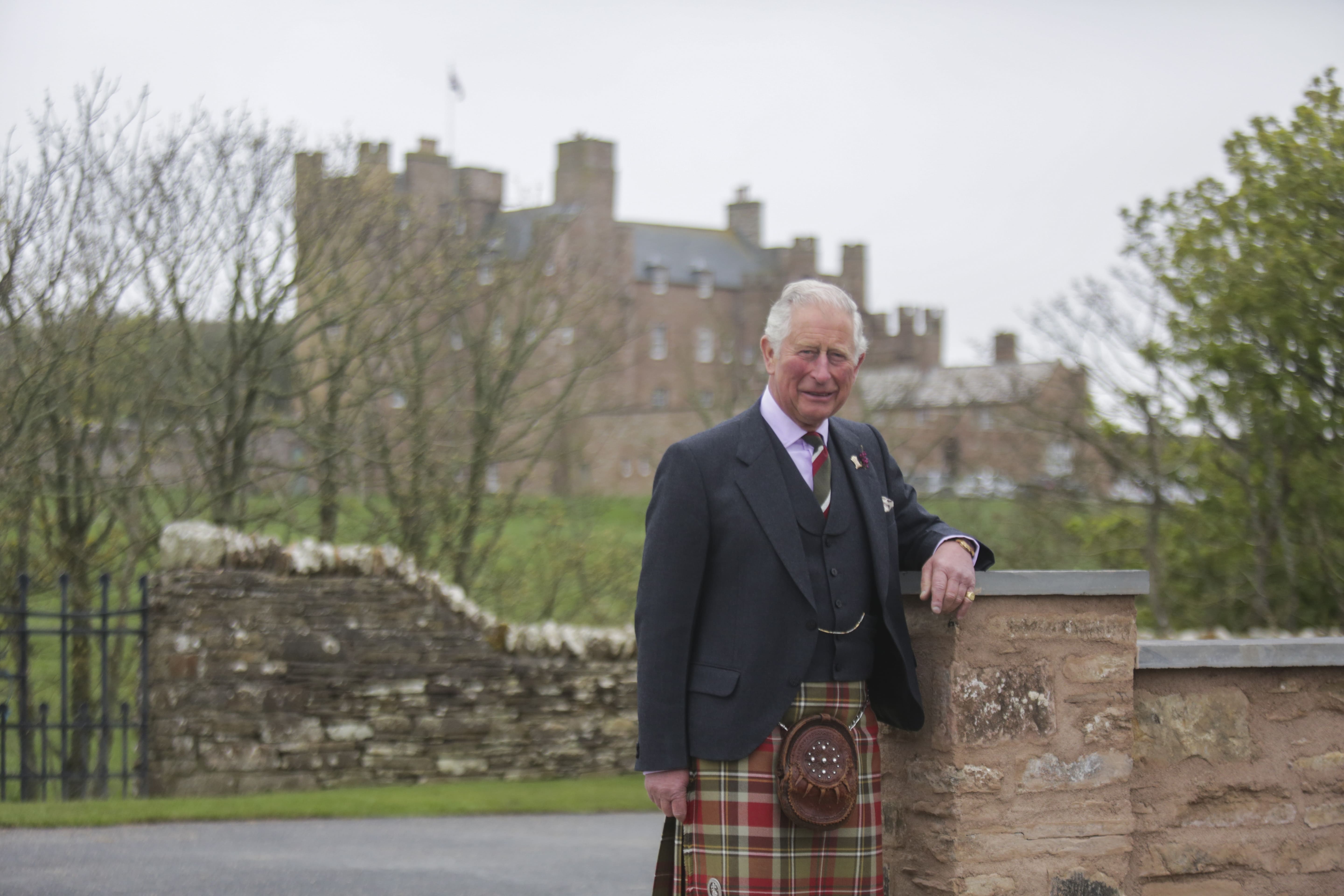 His Majesty King Charles III beside a stone wall in the grounds of the Castle of Mey, wearing traditional Highland dress.