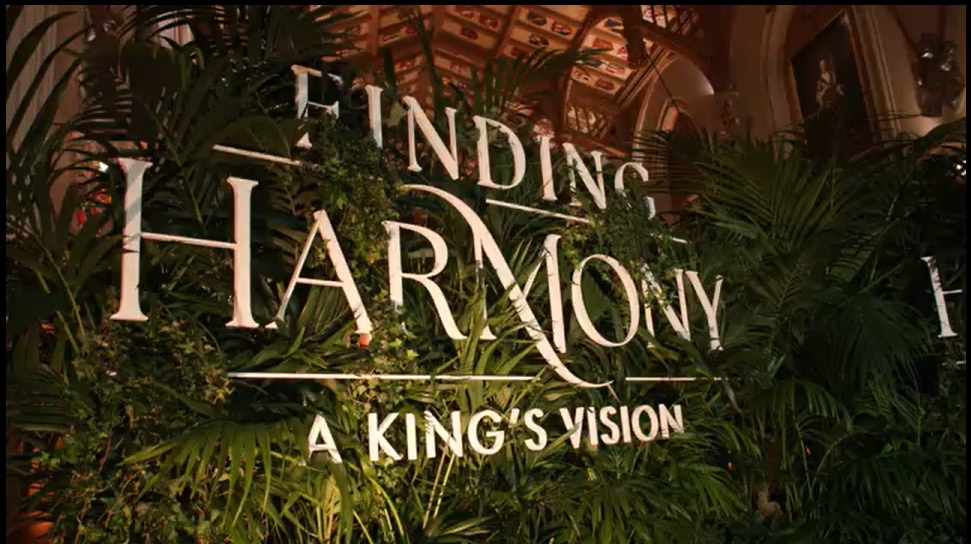 Lush green foliage wall displaying the Finding Harmony: A King’s Vision title at the film premiere.