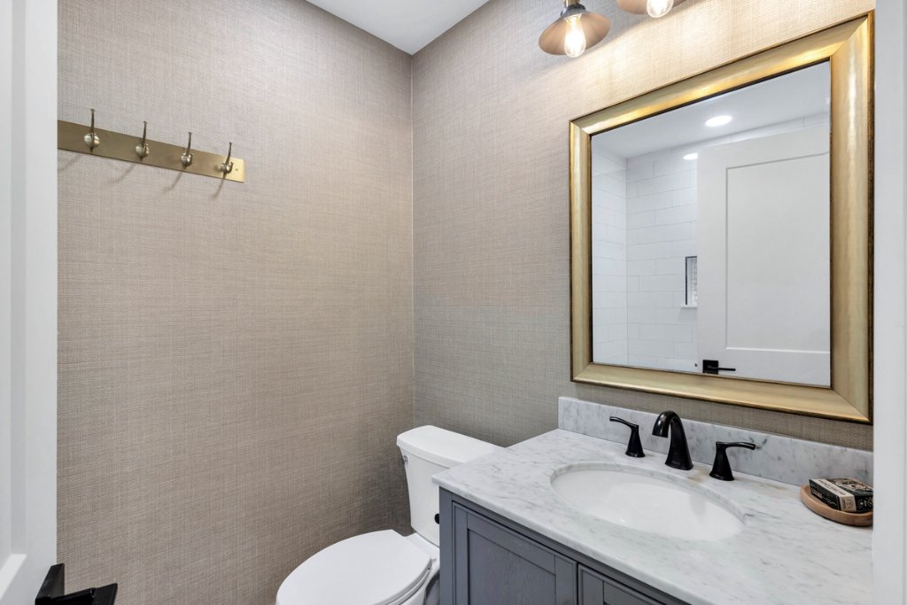 Luxury bathroom with marble countertop, gold-framed mirror, brass fixtures, and textured walls after Blueprint Construction remodel — Golden Isles, GA