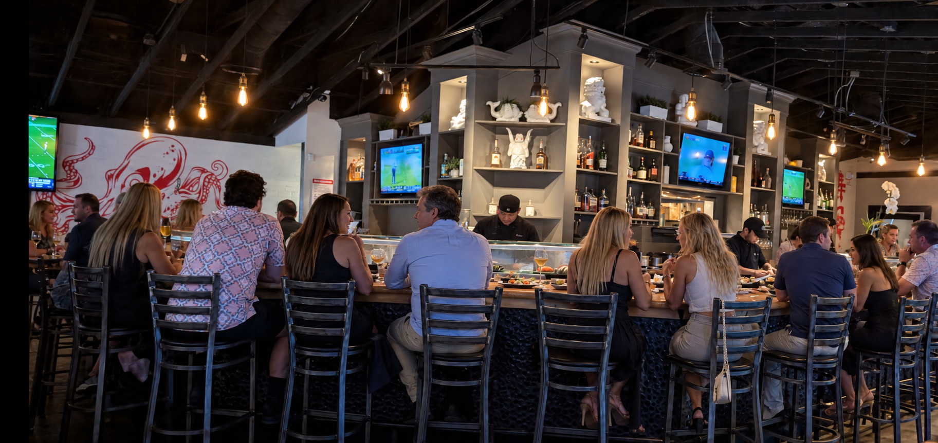 Sushi Brokers bar interior on a Tuesday night with patrons seated at the sushi bar, warm lighting, and shelves of liquor behind the counter