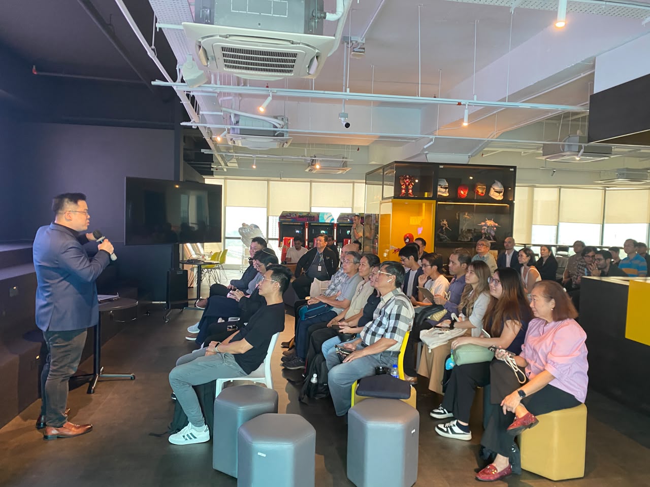 Eli Hong presenting to a seated audience at a modern training venue