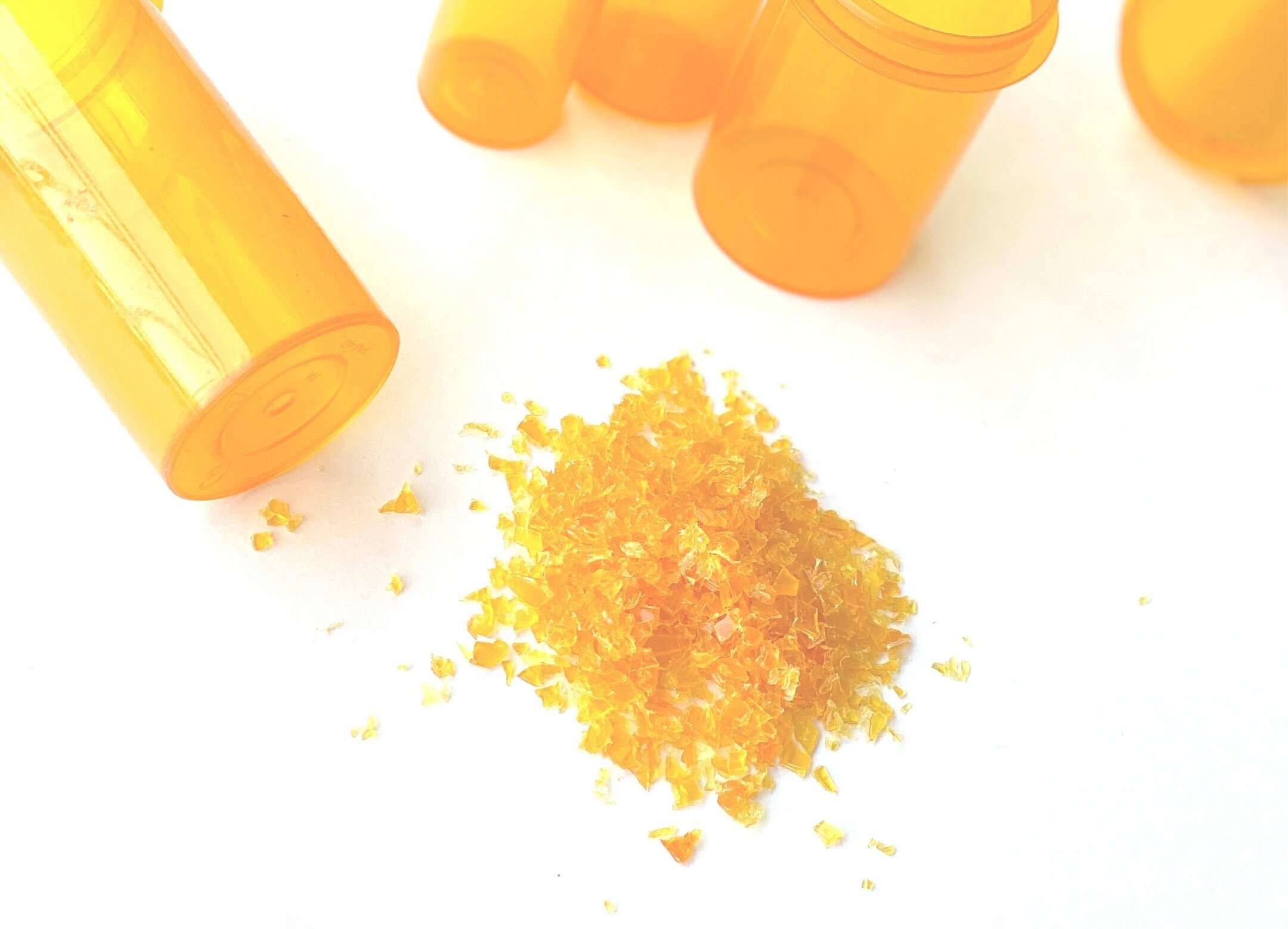 Orange packaging containers beside a pile of orange material flakes