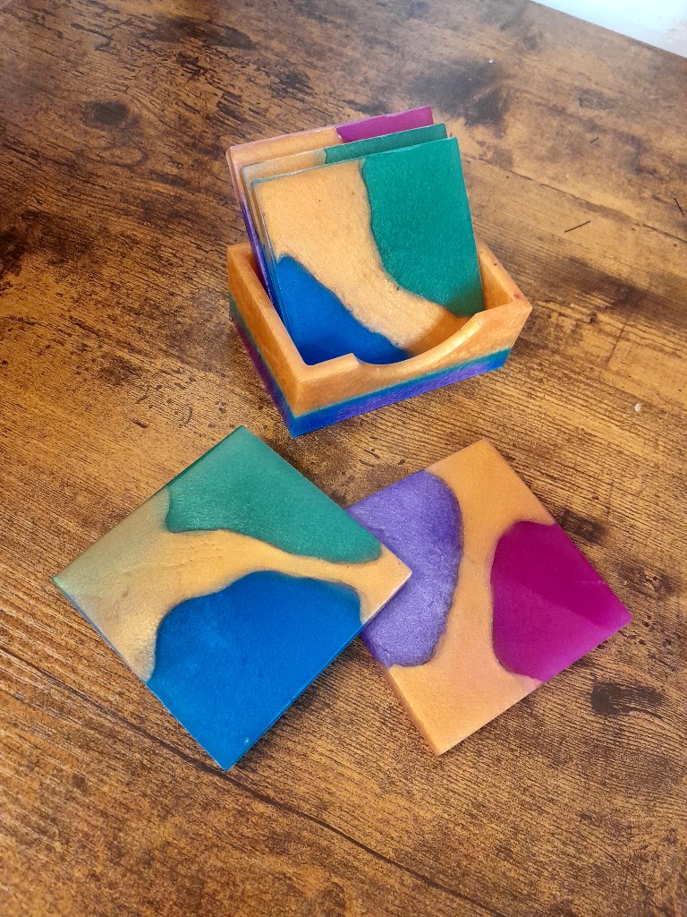 Resin coaster holder with square coasters in blue green gold purple and magenta