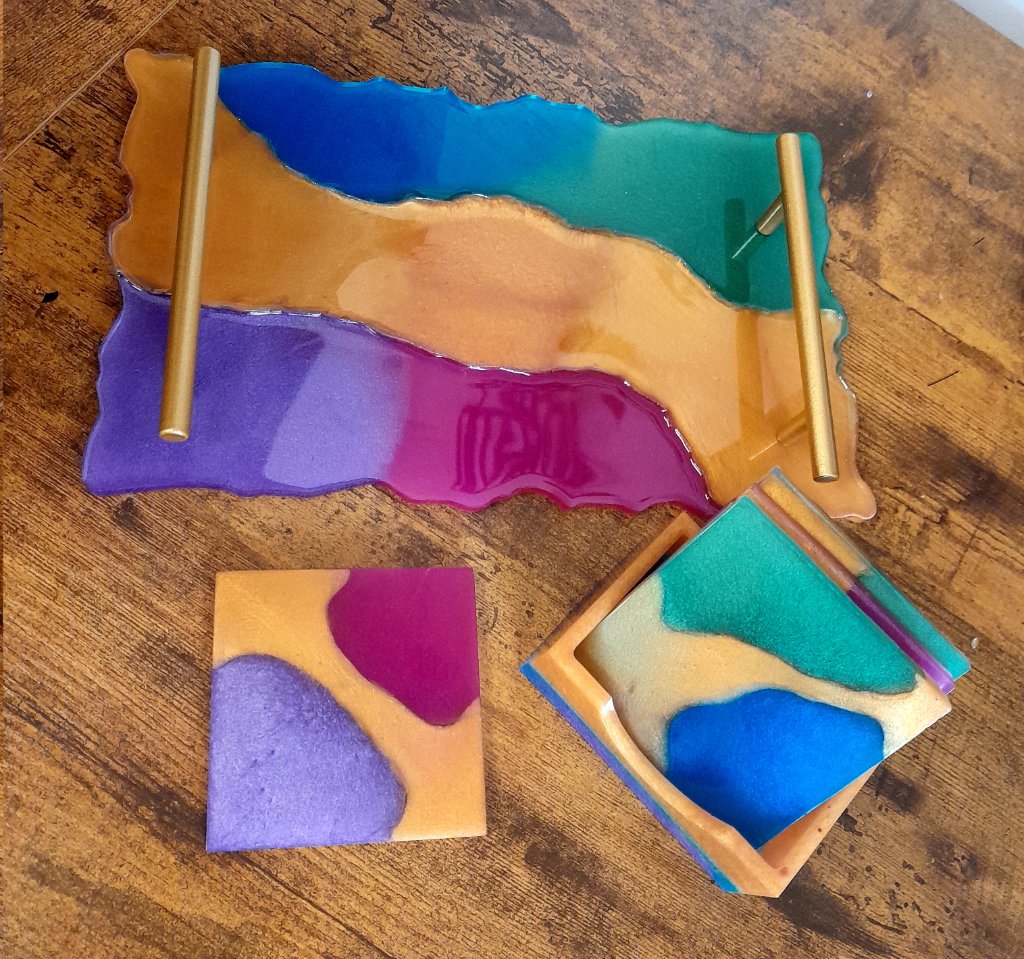 Resin tray and coaster set with blue green amber magenta and violet bands on wood