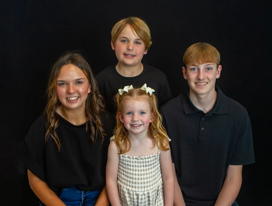 Studio portrait of siblings on a dark backdrop at the Plain Dealing studio