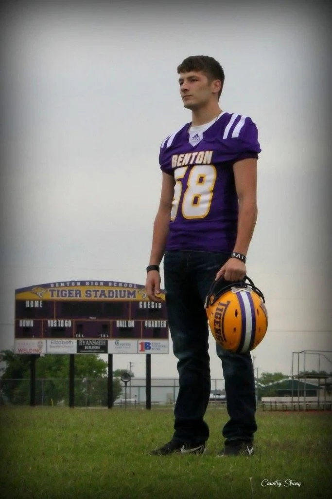 Football player holding his helmet, photographed at the stadium