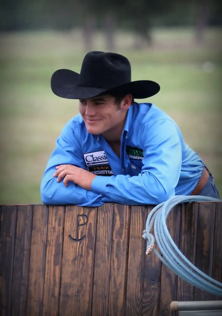Senior portrait of a student leaning on a wooden fence