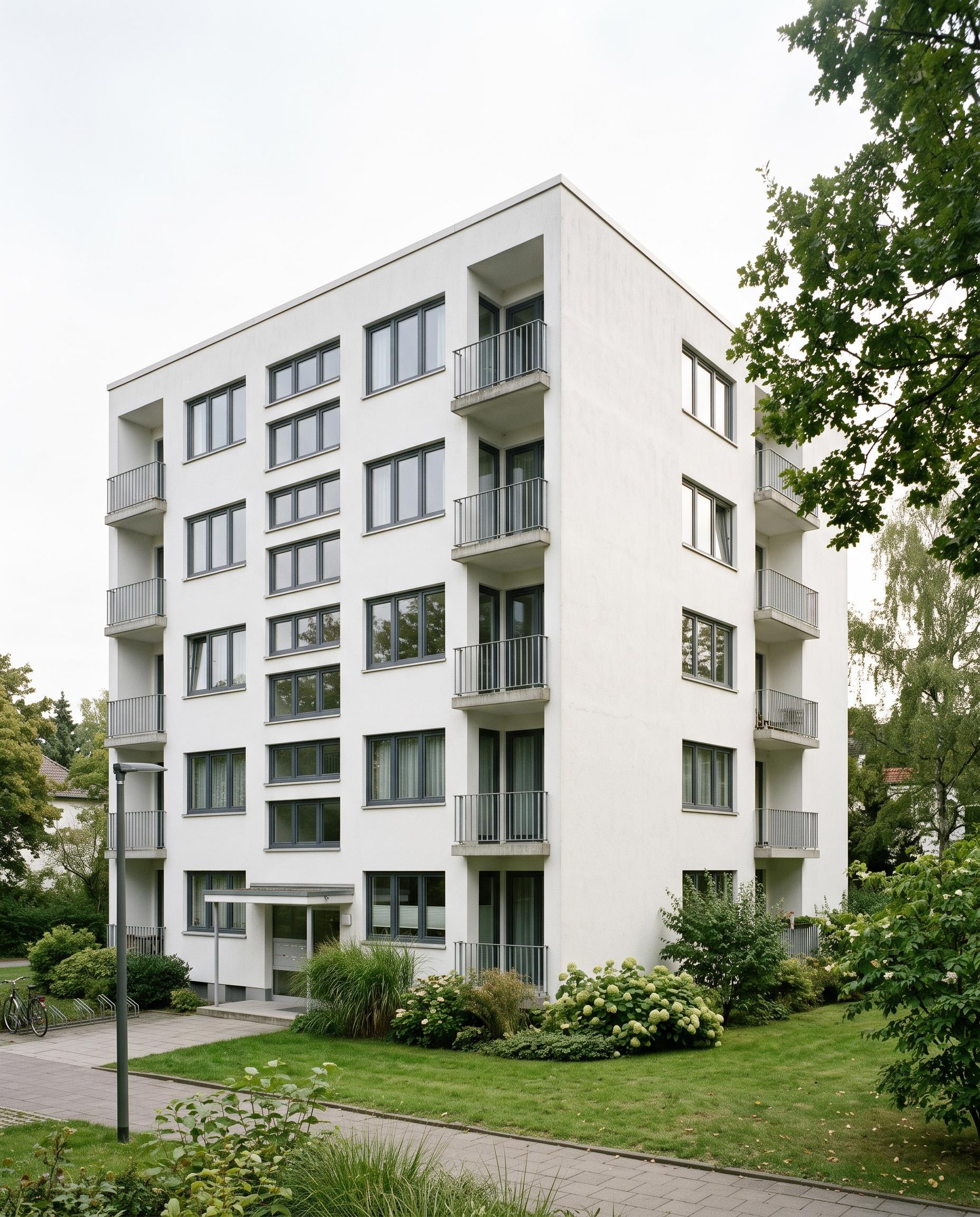 Bestandswohnhaus mit weißer Putzfassade und klarer Kubatur in hellem Tageslicht