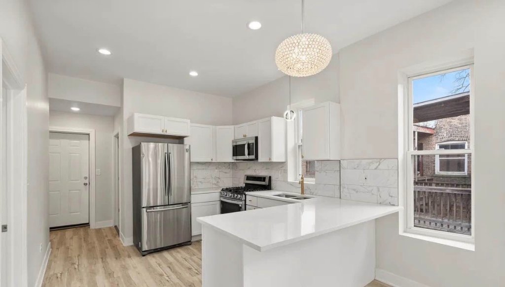 Open-concept kitchen and living space with quartz island and linear fireplace by Remodeling Kings