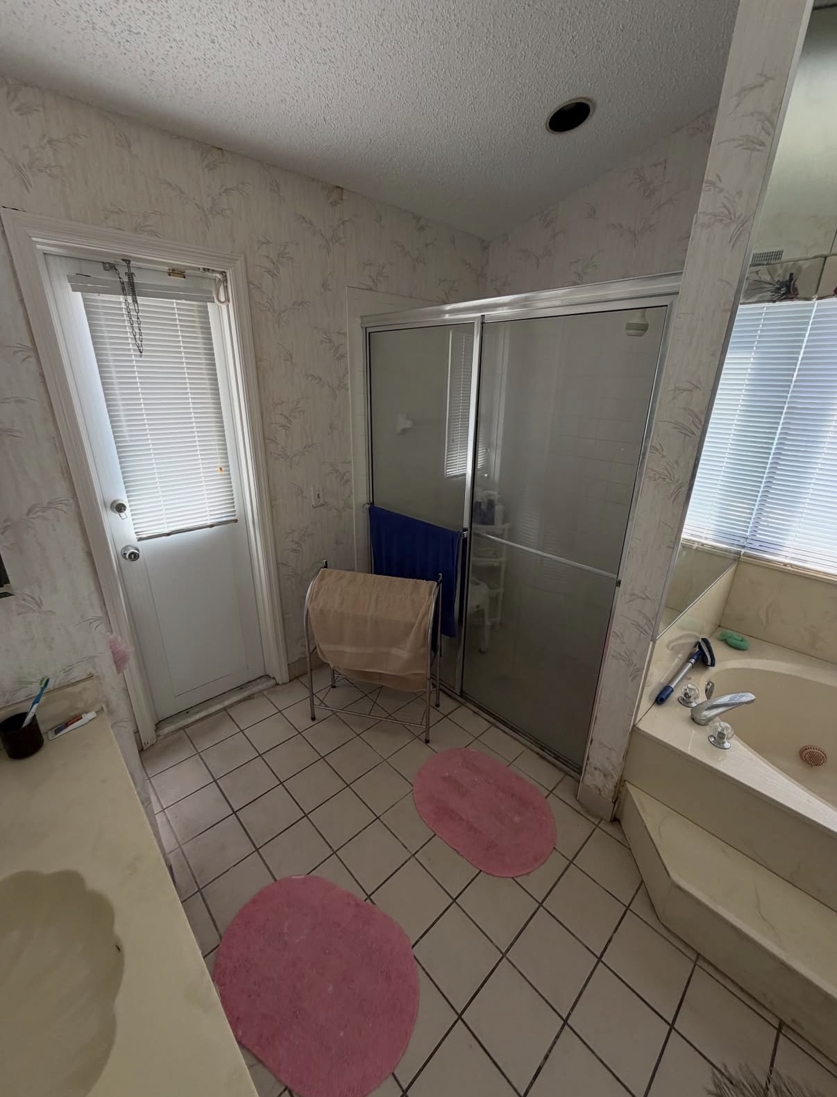 Before bathroom remodeling in Hinsdale, IL — outdated jetted tub, floral wallpaper, and mirrored alcove