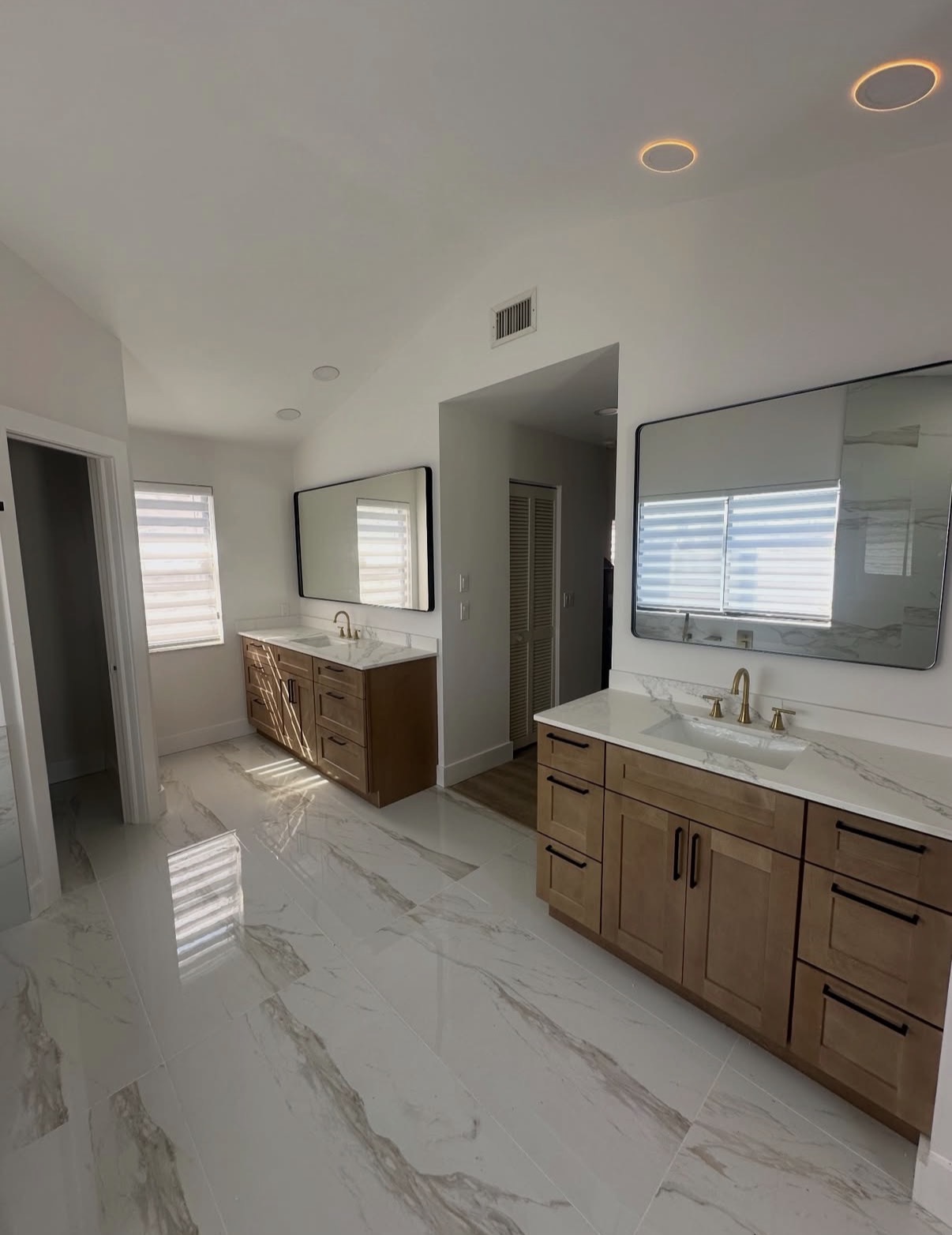 Completed bathroom renovation in Hinsdale, IL — double vanity, marble-look floor, and vaulted ceiling