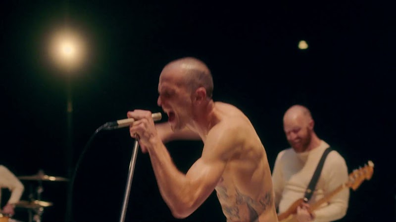JMSN shirtless singing into a vintage microphone on stage
