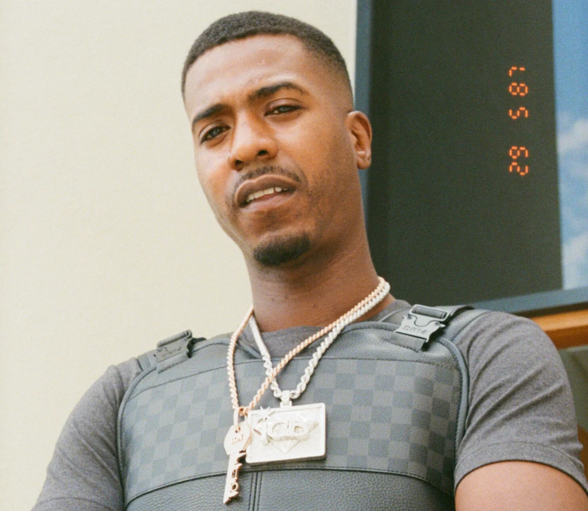 Nines photographed from a low angle wearing a tactical chest rig with an ICB pendant, with a vintage date stamp overlay reading 29 5 87.