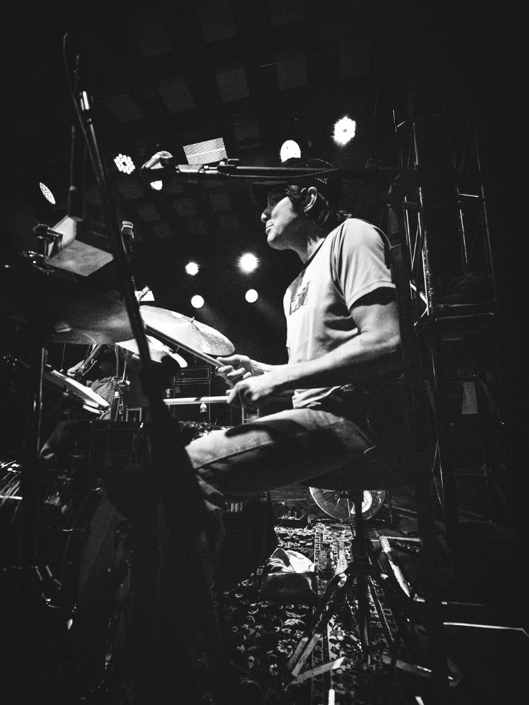 The drummer locked in during the Brazil tour — black and white shot from stage level