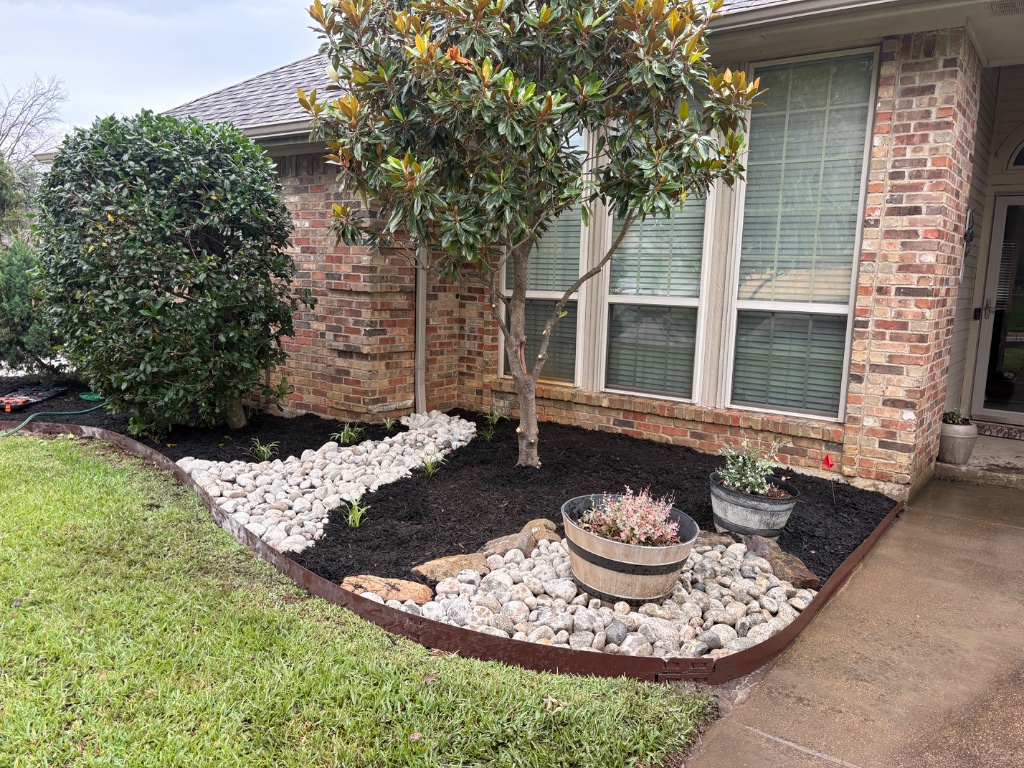 River rock dry creek bed landscaping with magnolia tree and metal edging in Arlington TX