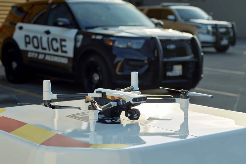 A police drone on a landing pad with a patrol vehicle in the background